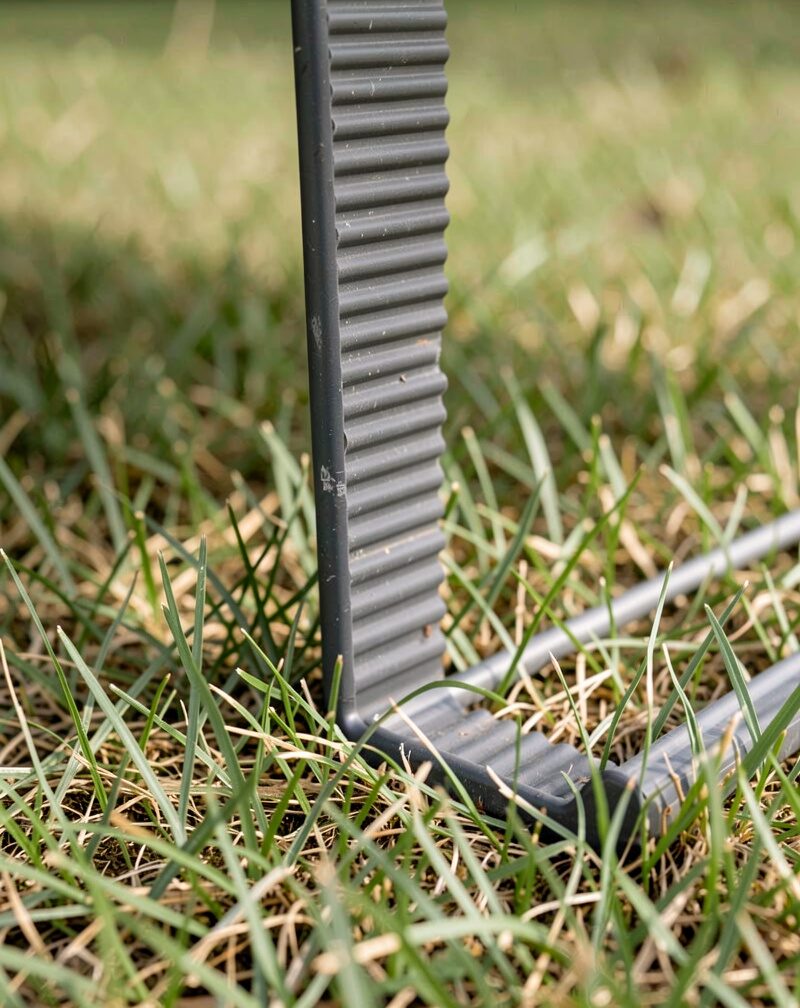 An empty wire arrow-frame stake pressed into a street-corner lawn pointing down the road, balloons tied to a mailbox beyond