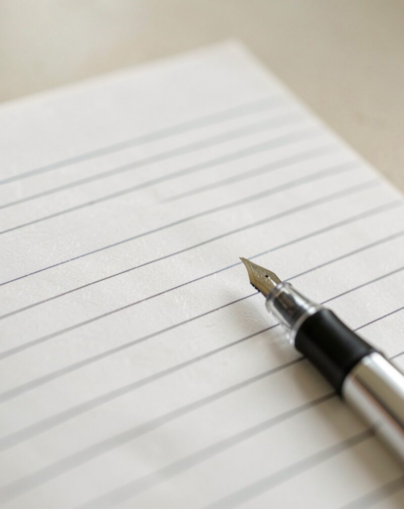 A blank ruled clipboard lying empty on a kitchen counter beside a plate of cookies, a pen resting across it